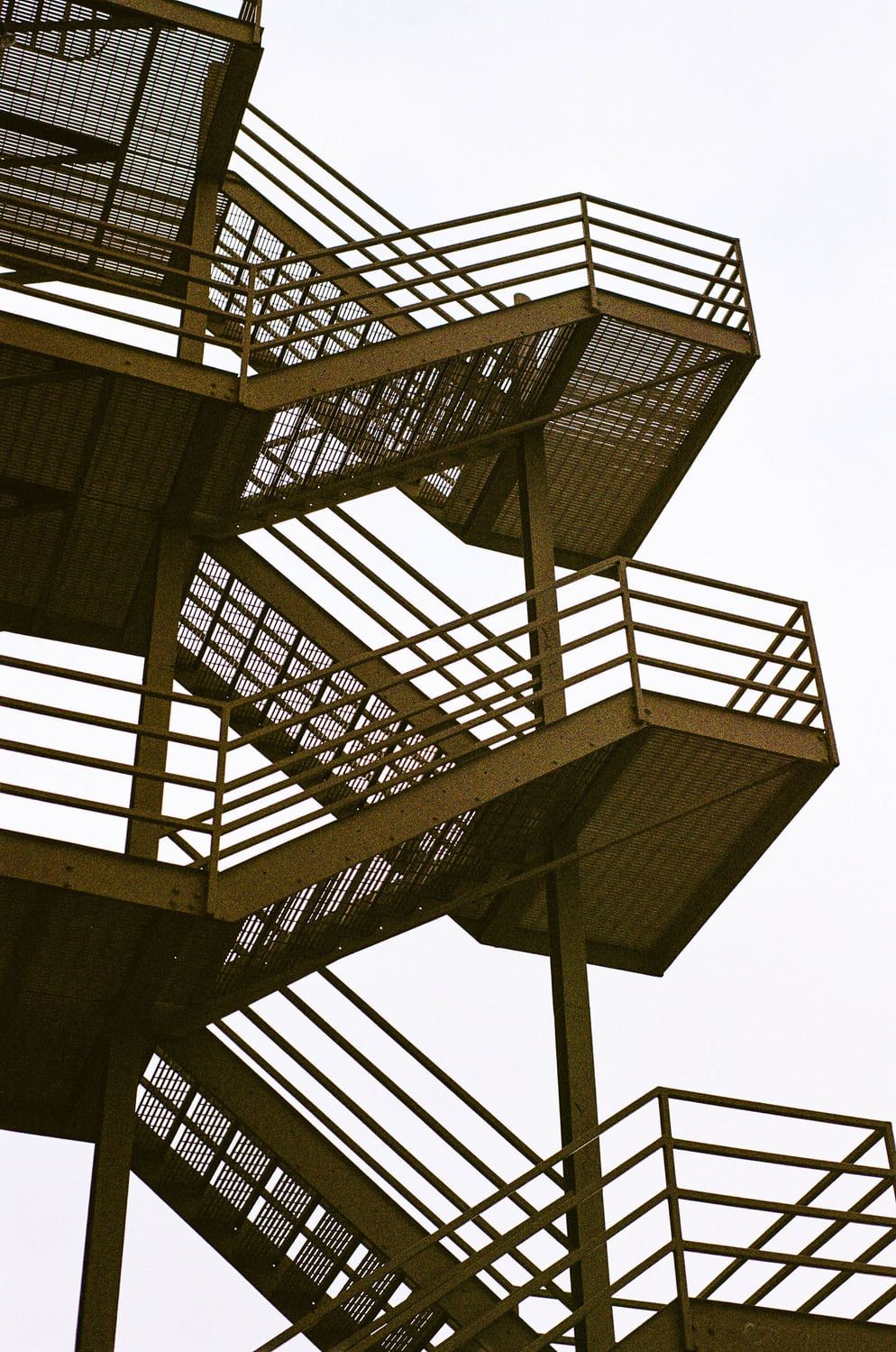 Stahltreppe mit mehreren Läufen, Podesten und Geländern vor hellem Himmel